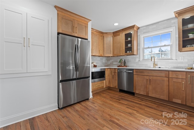 kitchen with stainless steel appliances, dark wood-style flooring, light countertops, and glass insert cabinets