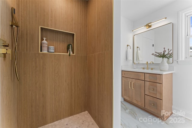 full bathroom with marble finish floor, tiled shower, and vanity