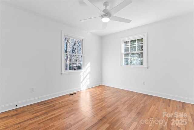 spare room with baseboards, ceiling fan, visible vents, and light wood-style floors