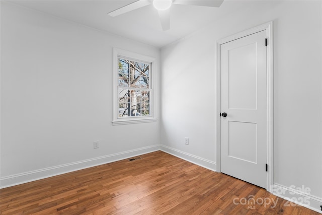 spare room featuring visible vents, wood finished floors, a ceiling fan, and baseboards