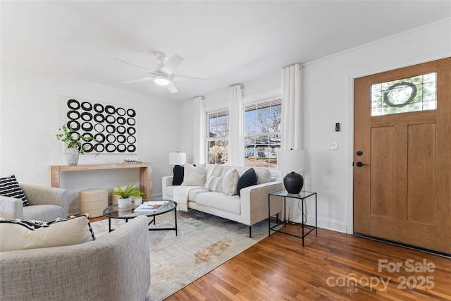 living area with plenty of natural light, baseboards, a ceiling fan, and wood finished floors