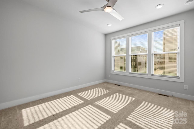 carpeted empty room with ceiling fan and plenty of natural light