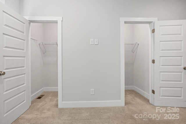 unfurnished bedroom with light carpet, a closet, and a walk in closet