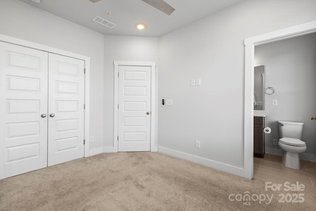 unfurnished bedroom featuring ceiling fan, ensuite bathroom, and light carpet