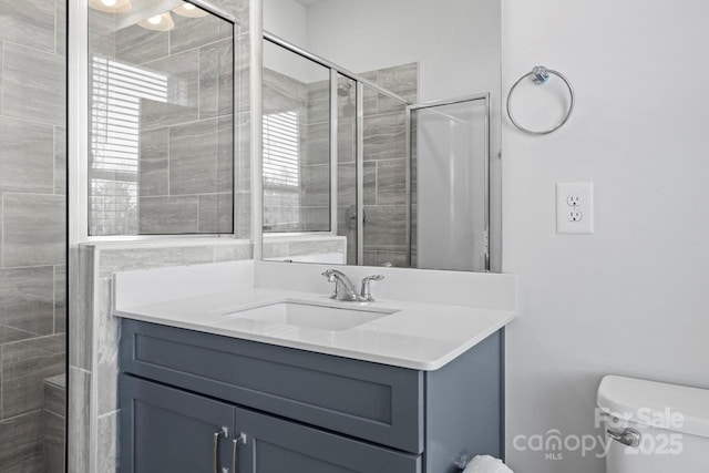 bathroom featuring vanity, toilet, and an enclosed shower