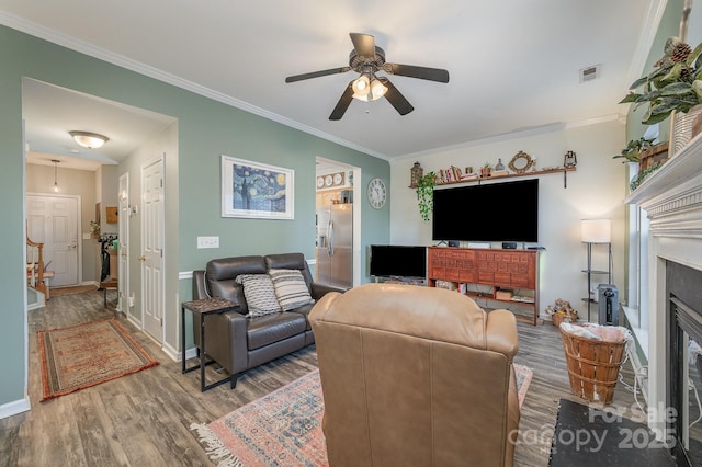 living room with hardwood / wood-style flooring, ceiling fan, and crown molding