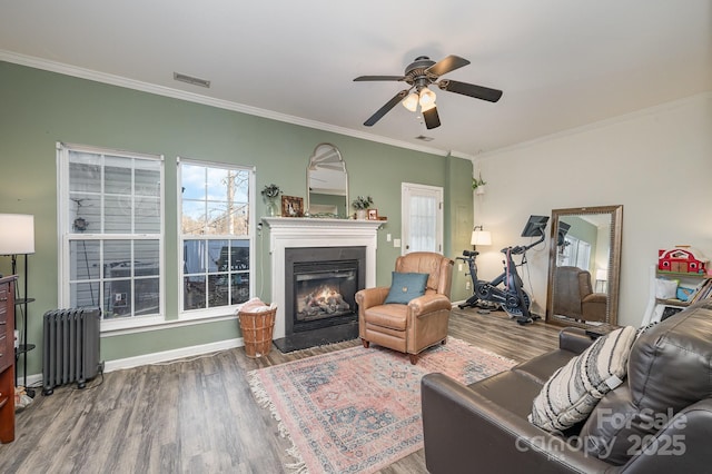 living room with ceiling fan, wood-type flooring, ornamental molding, and radiator