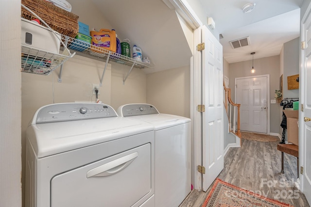 washroom featuring washing machine and dryer and light hardwood / wood-style flooring