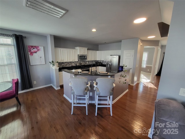 kitchen with white cabinetry, a breakfast bar area, stainless steel appliances, and dark hardwood / wood-style floors