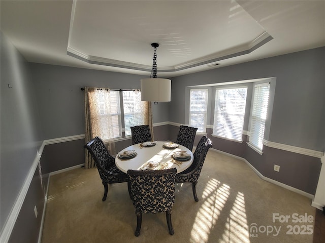 dining space featuring light colored carpet, a raised ceiling, and a healthy amount of sunlight