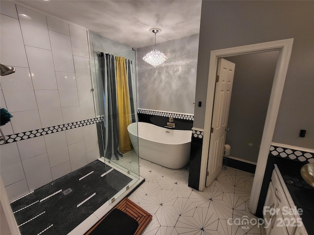 bathroom with tile patterned flooring, tile walls, a notable chandelier, and a bathtub