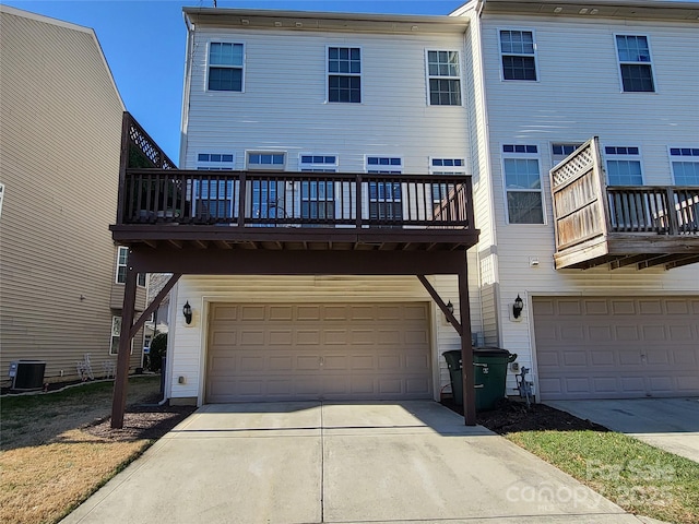 rear view of house featuring a garage, central AC, and a balcony