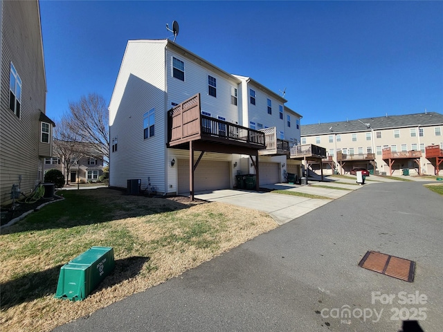 exterior space featuring central AC, a garage, and a lawn