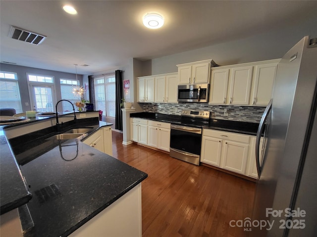 kitchen featuring decorative light fixtures, sink, white cabinets, backsplash, and stainless steel appliances