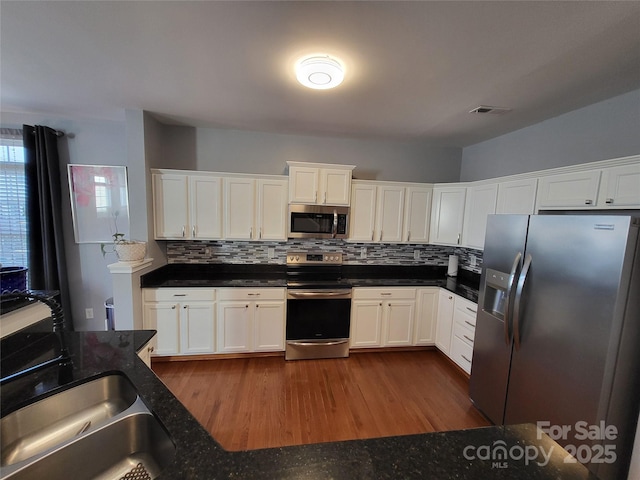 kitchen featuring dark hardwood / wood-style floors, sink, white cabinets, backsplash, and stainless steel appliances