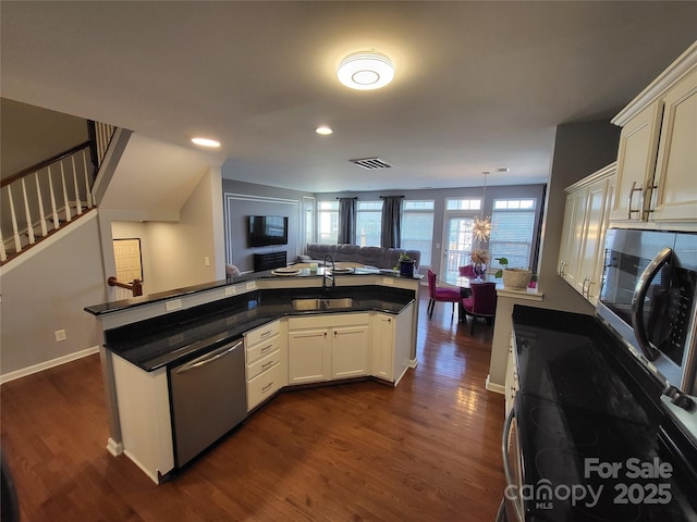 kitchen with hanging light fixtures, white cabinetry, appliances with stainless steel finishes, and sink