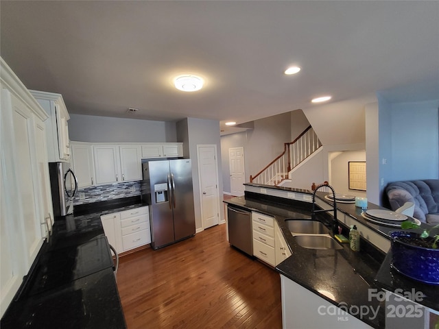 kitchen featuring white cabinetry, sink, dark stone counters, decorative backsplash, and stainless steel appliances