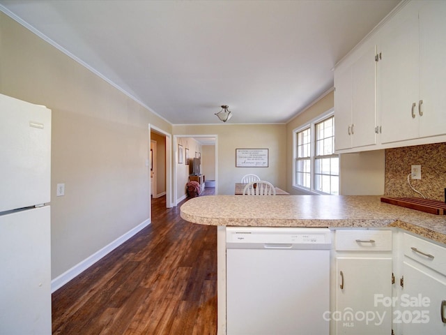 kitchen featuring tasteful backsplash, dark hardwood / wood-style floors, kitchen peninsula, white appliances, and white cabinets