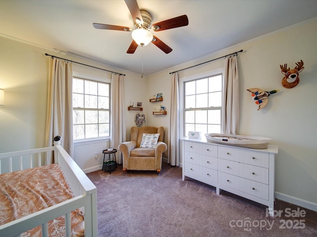 bedroom featuring dark colored carpet, a nursery area, ceiling fan, and crown molding