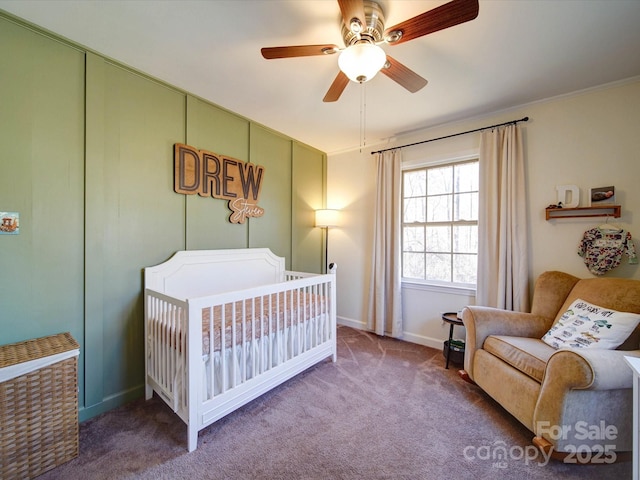 carpeted bedroom with ceiling fan, ornamental molding, and a nursery area