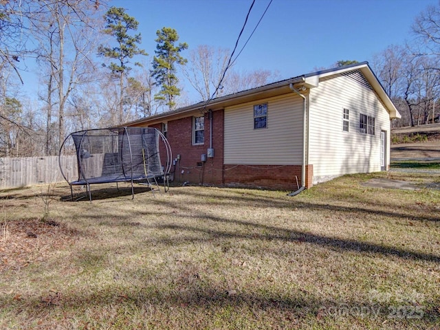 back of house featuring a trampoline and a lawn