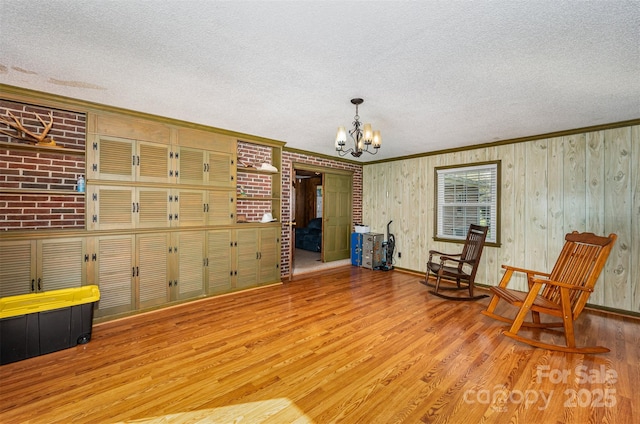 living area featuring a chandelier, wood-type flooring, a textured ceiling, and crown molding