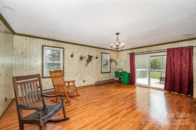 living area with hardwood / wood-style flooring, a notable chandelier, a wealth of natural light, and a baseboard radiator