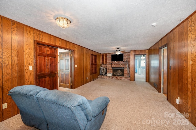 living room with carpet flooring, wooden walls, a fireplace, and a textured ceiling