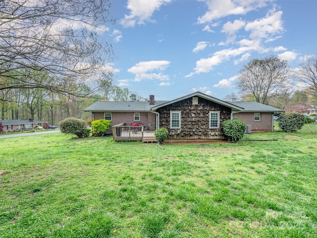 rear view of house featuring a lawn and a wooden deck