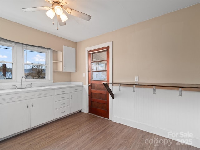 kitchen featuring white cabinets, ceiling fan, sink, and light hardwood / wood-style flooring