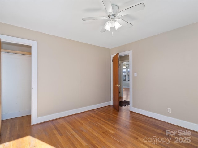 unfurnished bedroom featuring ceiling fan, wood-type flooring, and a closet