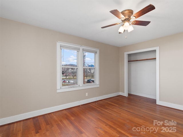 unfurnished bedroom with ceiling fan, a closet, and wood-type flooring