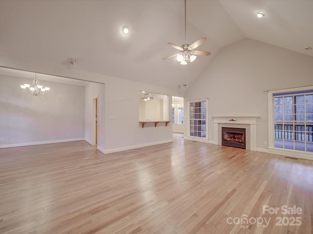 unfurnished living room featuring ceiling fan with notable chandelier, high vaulted ceiling, and light hardwood / wood-style flooring