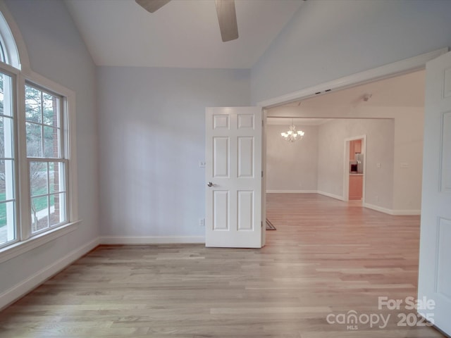 unfurnished room with ceiling fan with notable chandelier, light wood-type flooring, and lofted ceiling