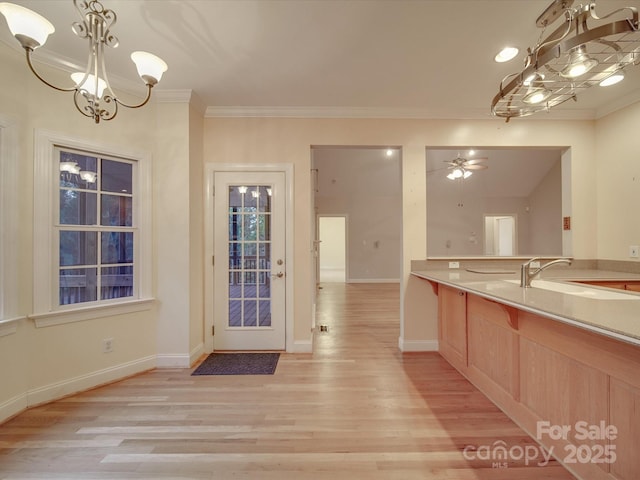 doorway to outside with sink, light hardwood / wood-style floors, ceiling fan with notable chandelier, and ornamental molding