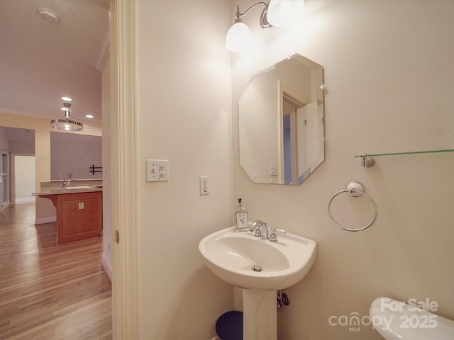 bathroom with toilet, hardwood / wood-style flooring, sink, and ornamental molding