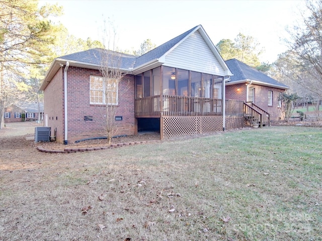 rear view of house with a lawn, a sunroom, and central AC unit