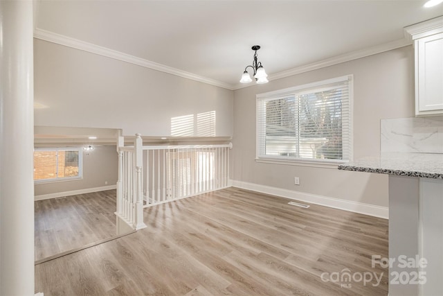 unfurnished dining area featuring light wood-type flooring, a wealth of natural light, and ornamental molding