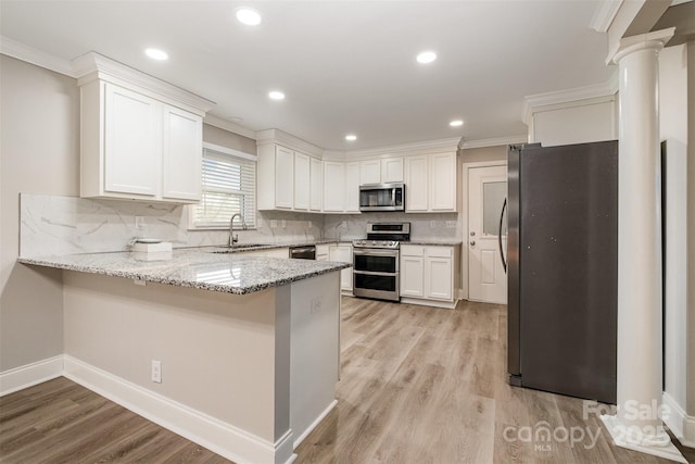 kitchen featuring backsplash, kitchen peninsula, white cabinetry, and stainless steel appliances