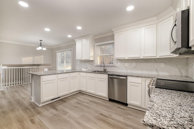 kitchen featuring white cabinetry, sink, stainless steel appliances, and decorative light fixtures