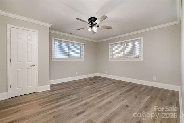 empty room featuring a wealth of natural light, ceiling fan, wood-type flooring, and ornamental molding