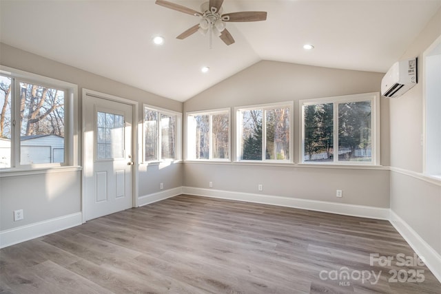 unfurnished sunroom with a wall unit AC, a wealth of natural light, ceiling fan, and lofted ceiling