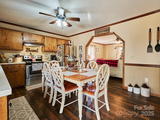 dining room featuring ceiling fan, ornamental molding, a textured ceiling, and dark wood-type flooring