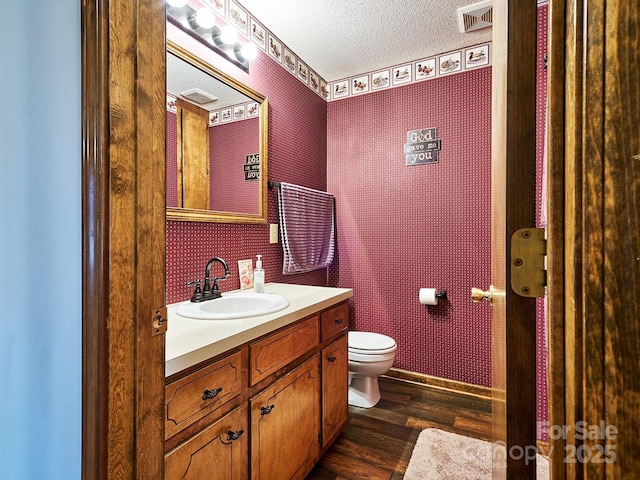 bathroom featuring hardwood / wood-style flooring, vanity, toilet, and a textured ceiling