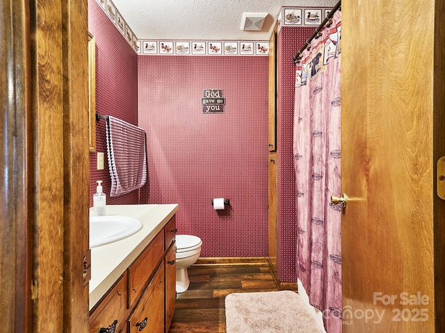 bathroom with vanity, wood-type flooring, a textured ceiling, and toilet