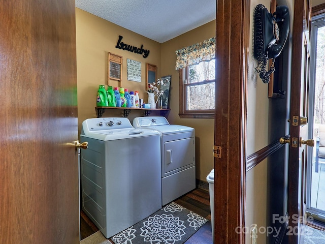 clothes washing area with a textured ceiling, washer and clothes dryer, and dark wood-type flooring