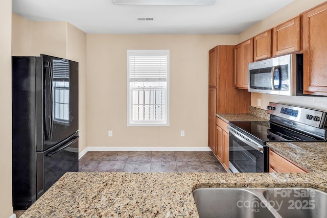 kitchen featuring light tile patterned floors, stainless steel appliances, and light stone counters