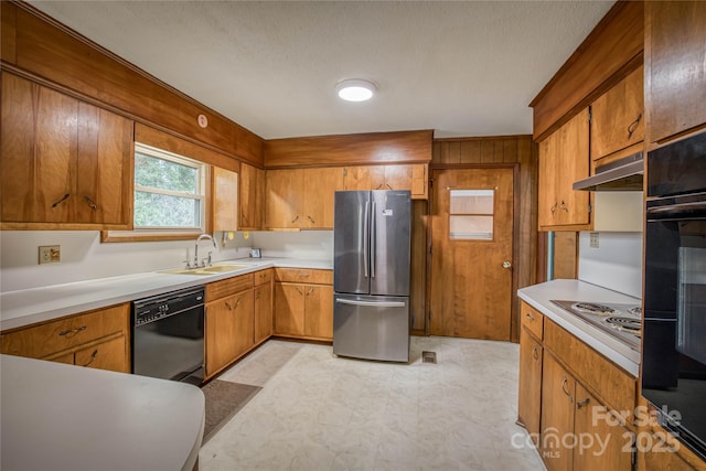 kitchen featuring black appliances, sink, and wooden walls