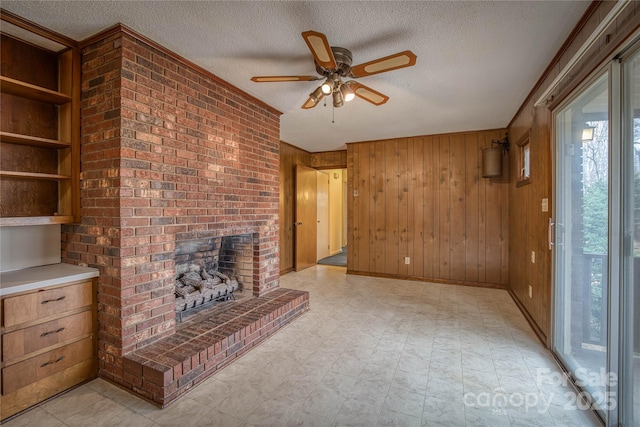 unfurnished living room featuring a wealth of natural light, wooden walls, ceiling fan, and a textured ceiling