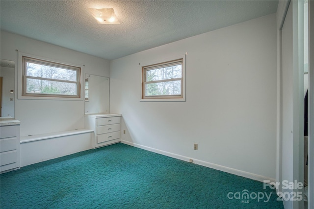 unfurnished bedroom with dark colored carpet and a textured ceiling